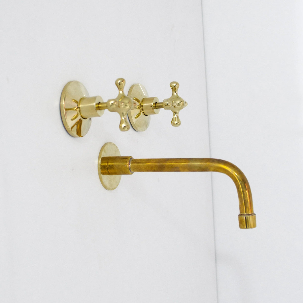Gold wall-mounted faucet and handle on a white background