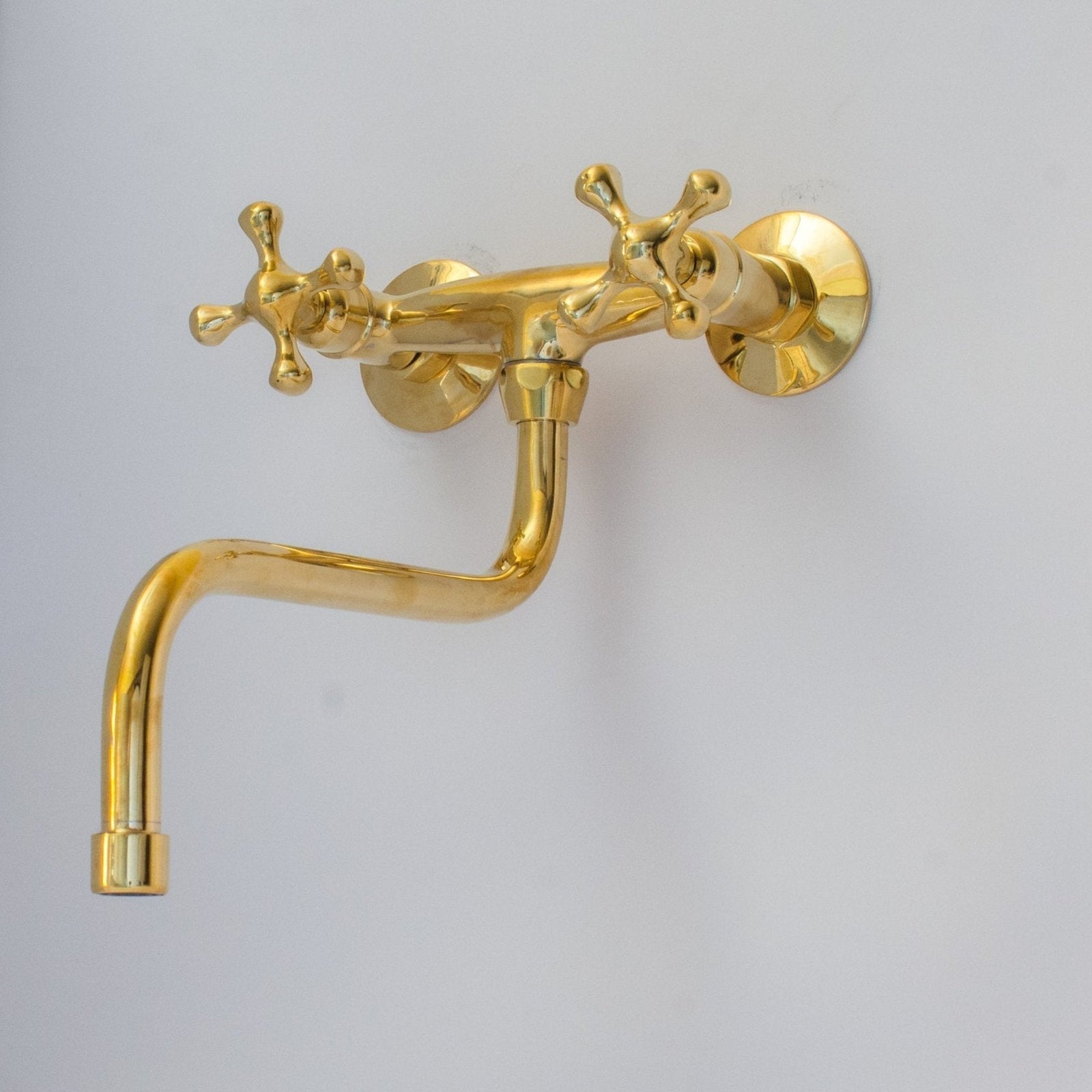 Gold wall-mounted faucet on a light gray background