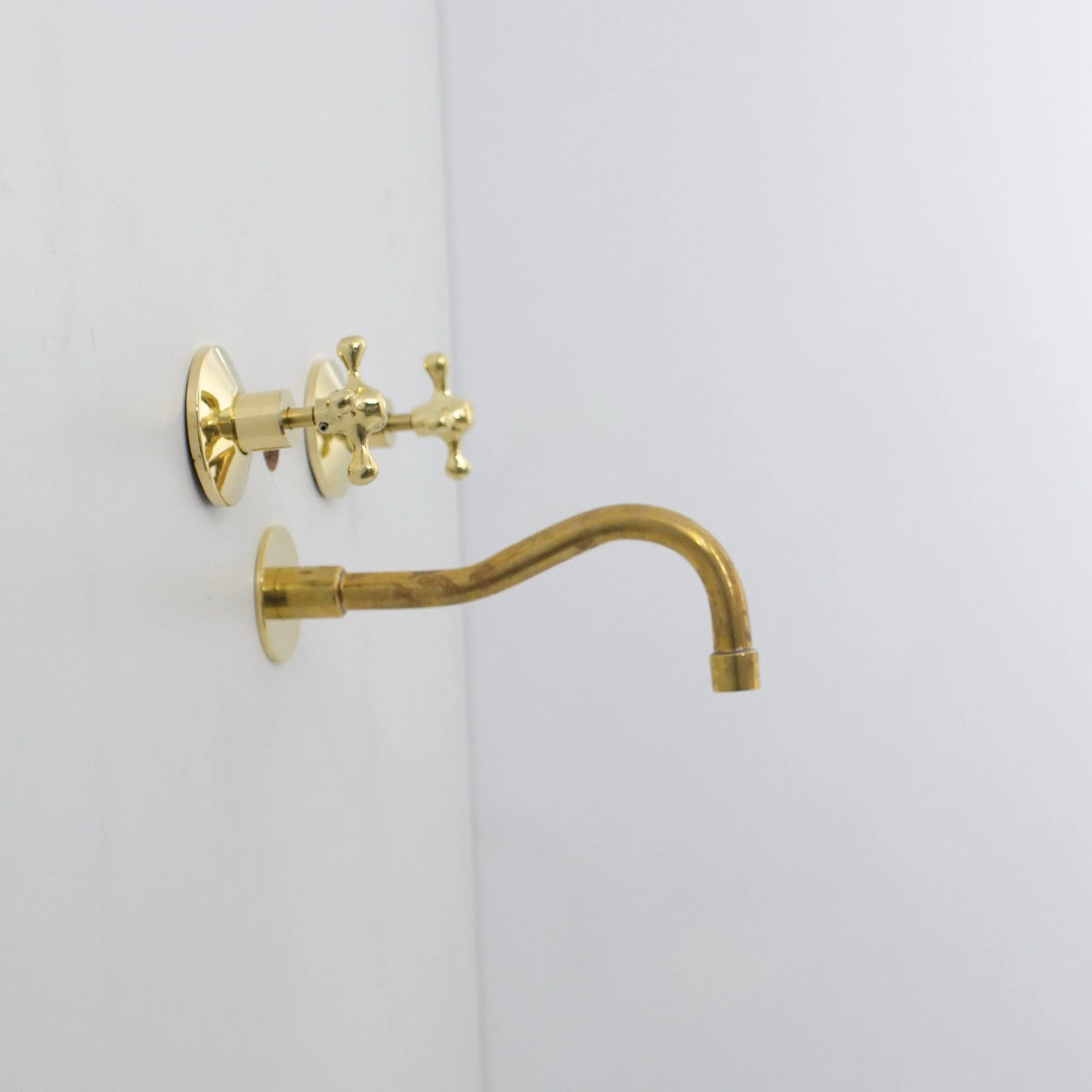 Gold wall-mounted faucet on a white background