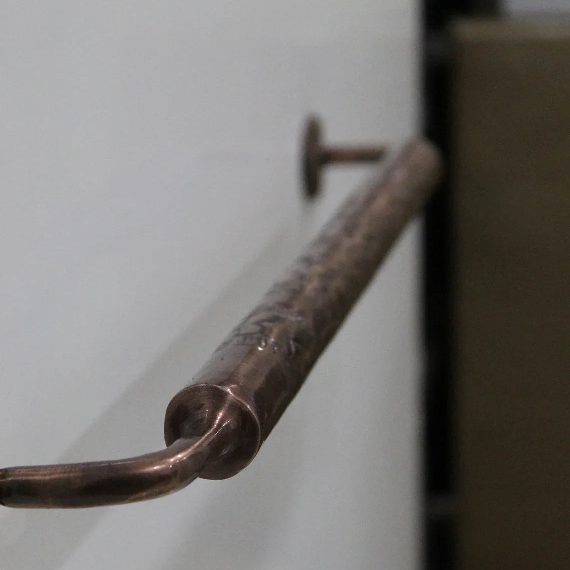 Copper handle on a white cabinet door