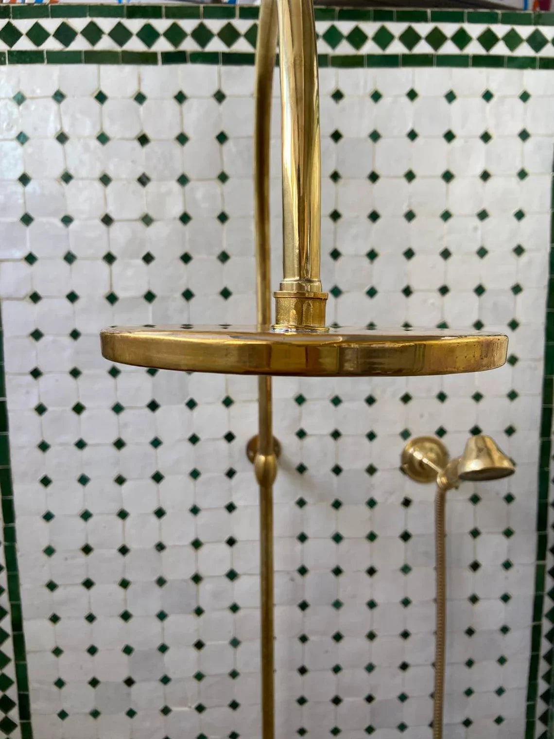 Gold shower head and fixtures against a green and white tiled wall