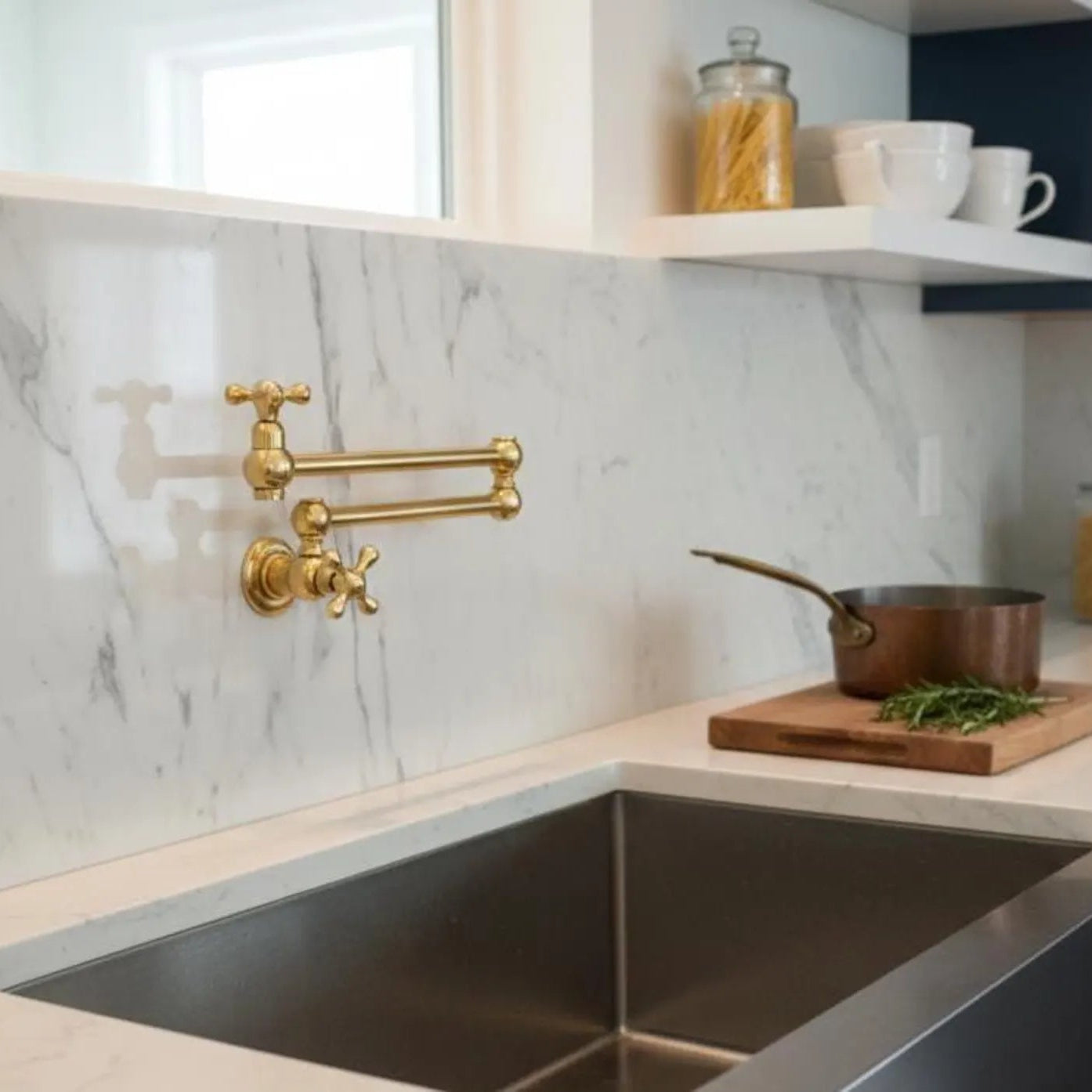 Modern kitchen with marble backsplash, gold faucet, and stainless steel sink.