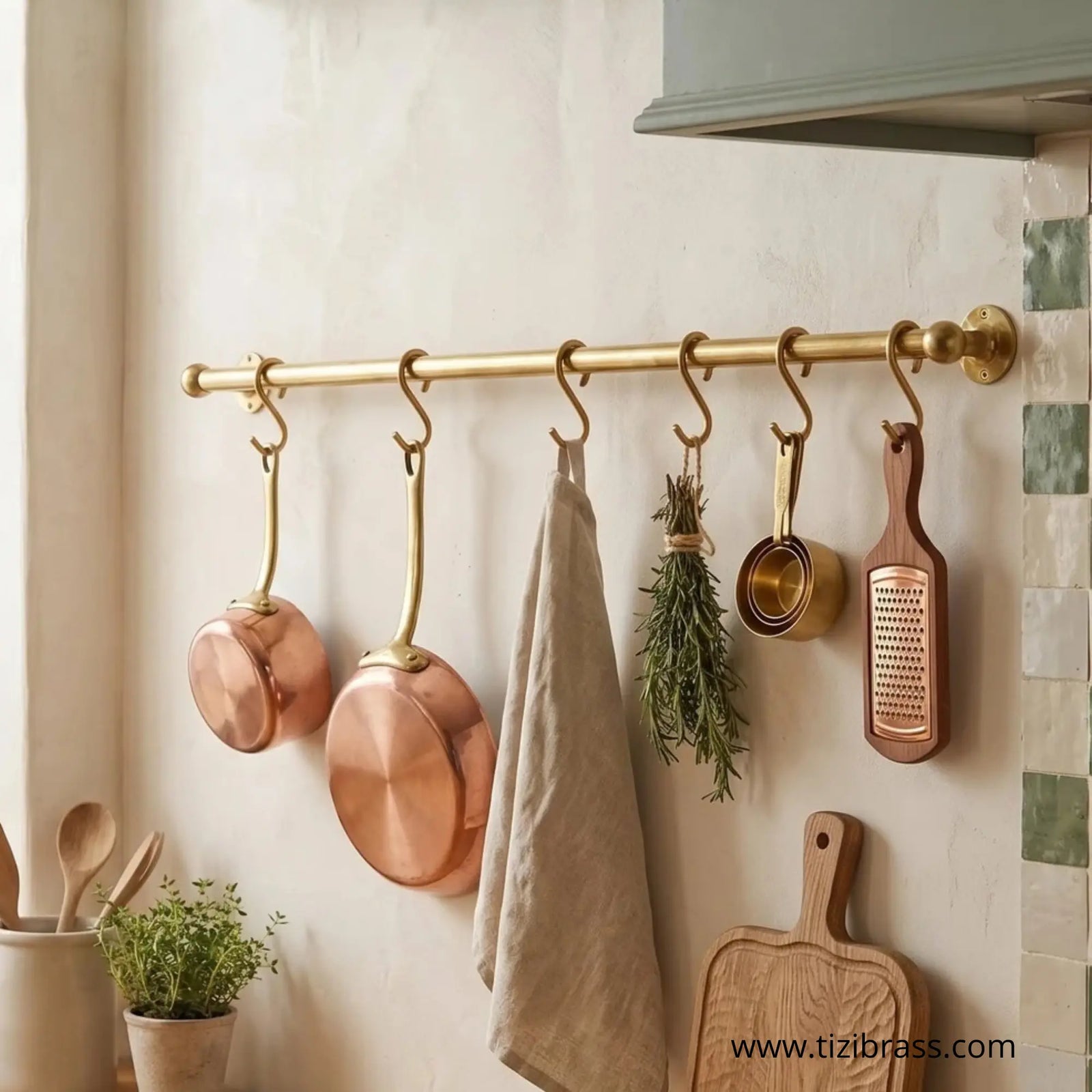 Unpolished solid brass wall-mounted kitchen rail holding copper pots, linen towel, and utensils - TiziBrass