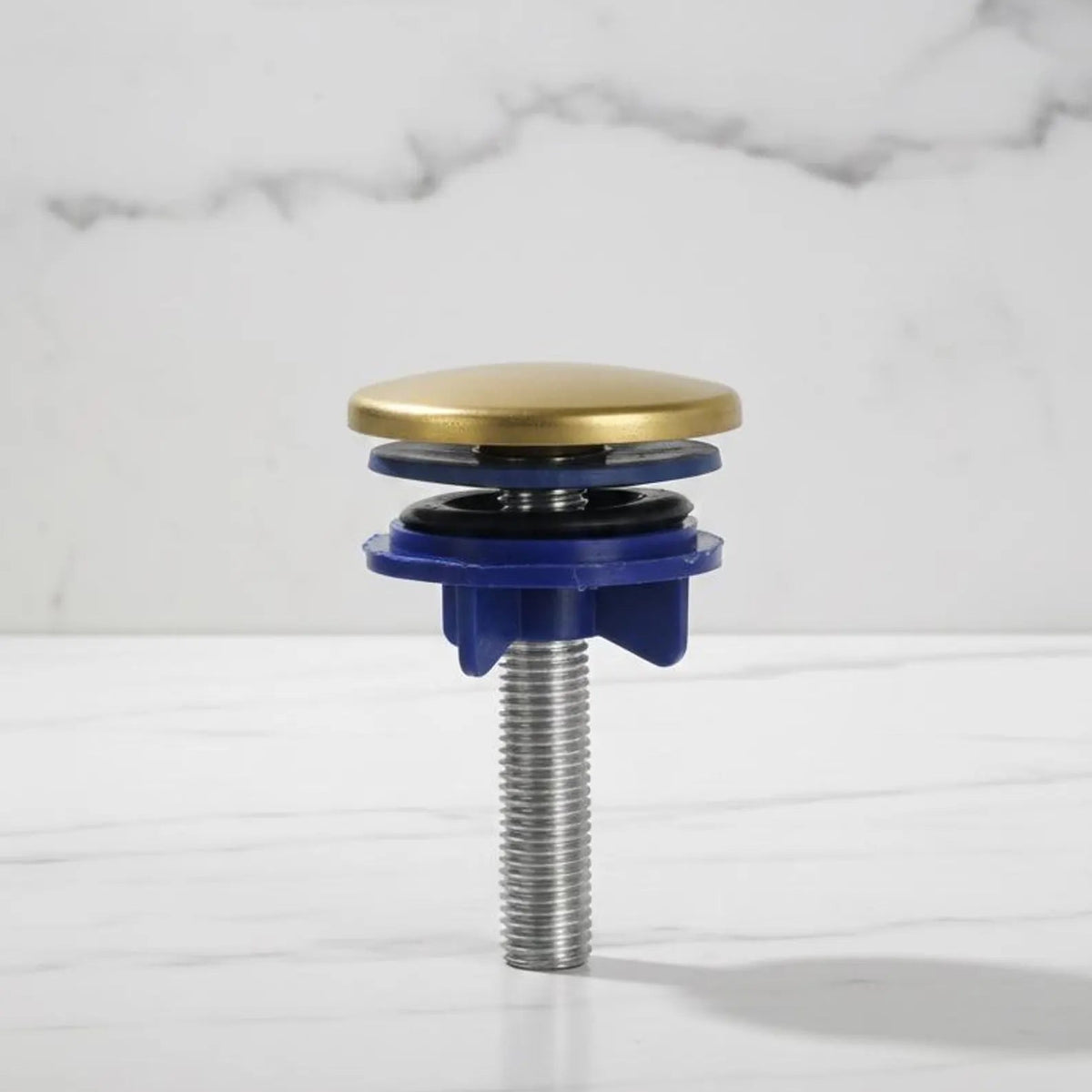 Plumbing drain trap with brass top and blue base on a marble background