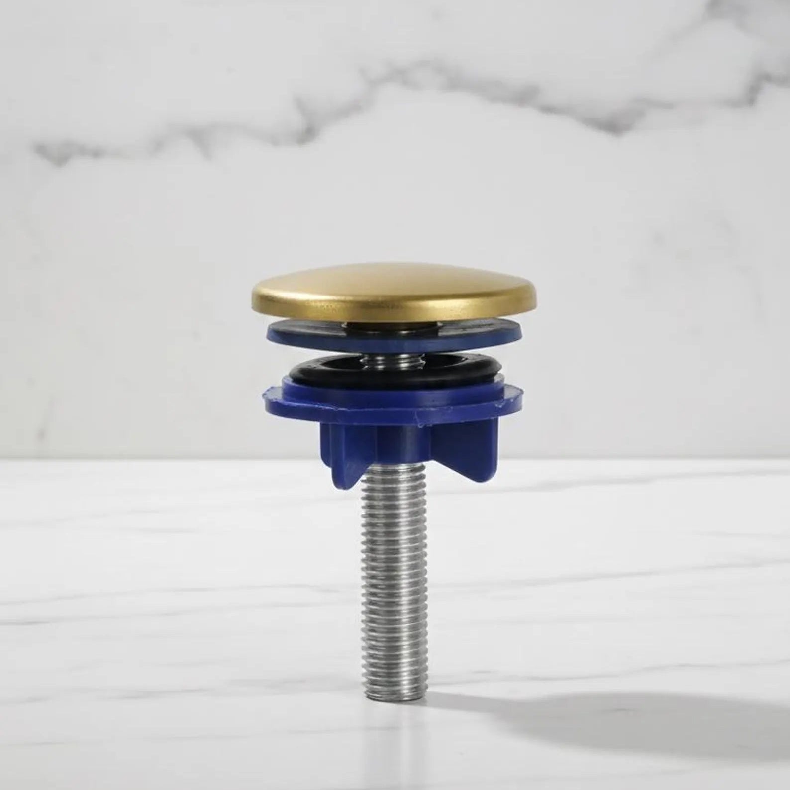 Plumbing drain trap with brass top and blue base on a marble background