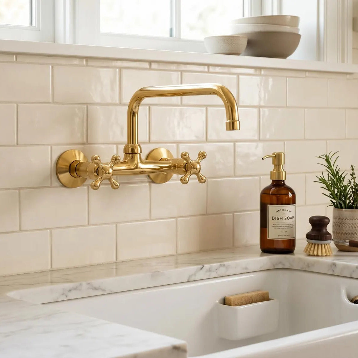 Gold kitchen faucet on a tiled wall with a sink and cleaning supplies.