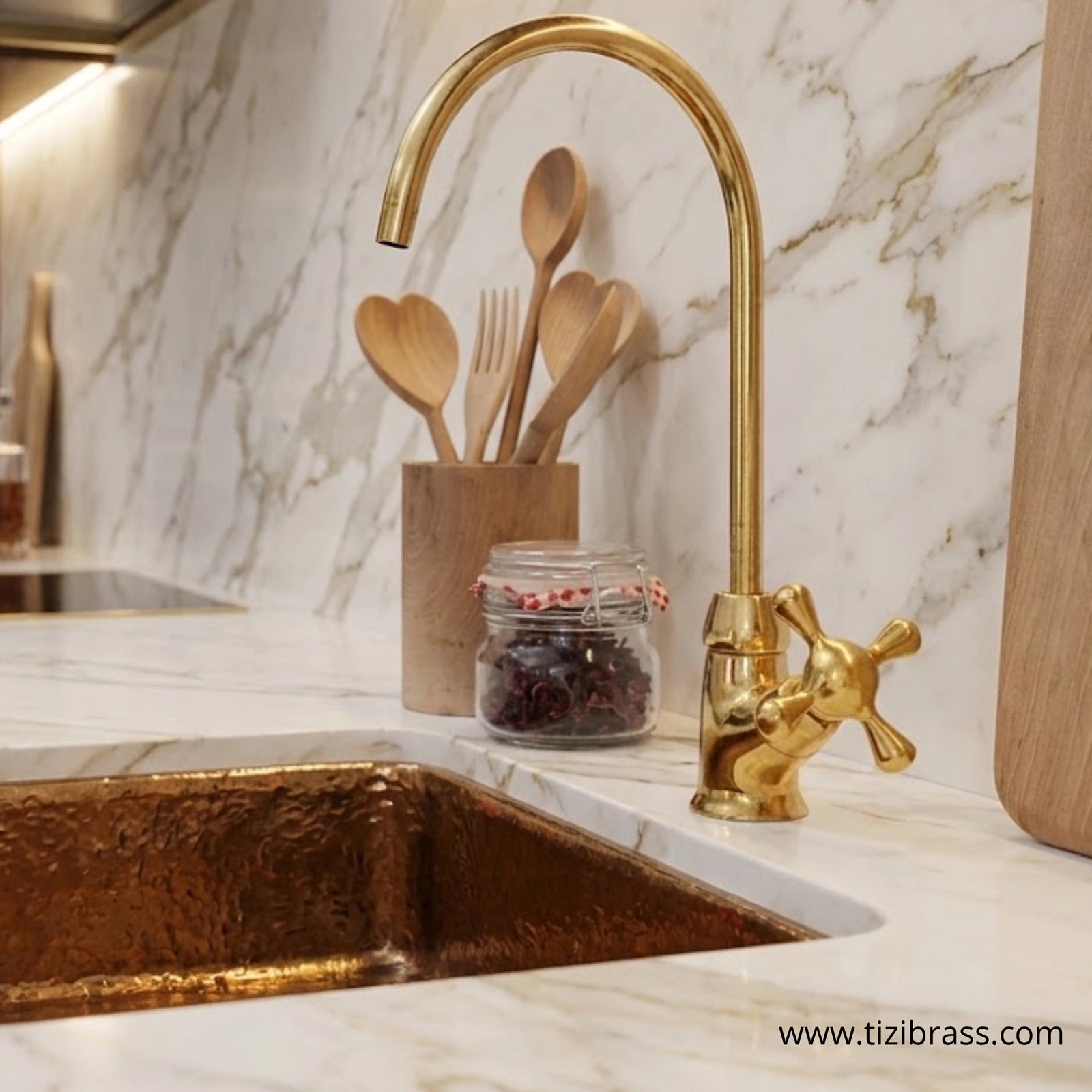 Unlacquered brass gooseneck water dispenser faucet on marble countertop with brass sink