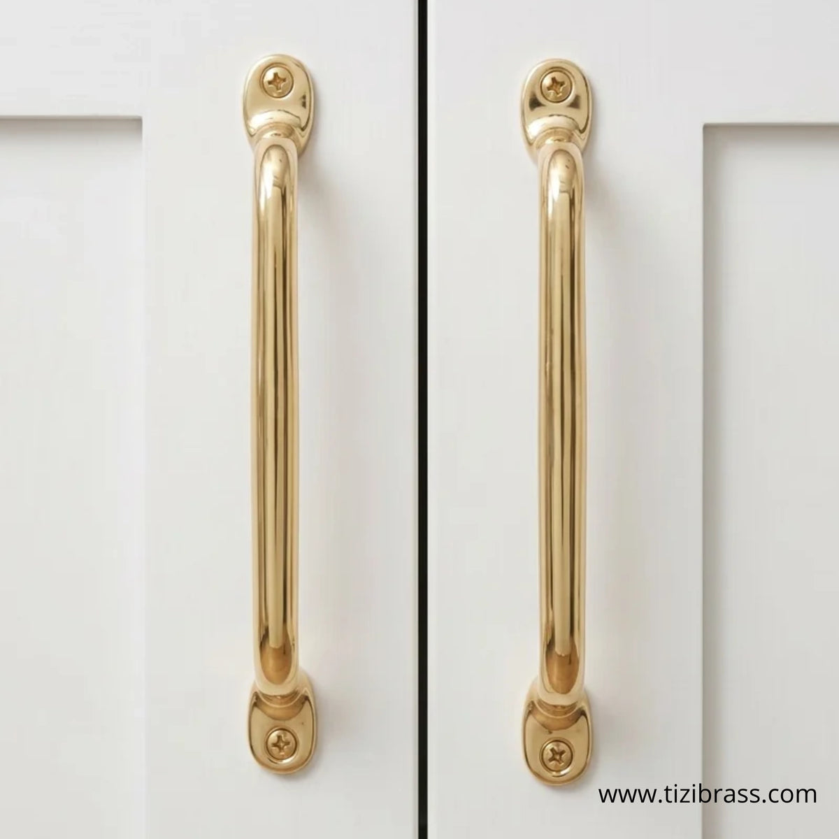 Unlacquered brass cabinet pulls close-up, solid brass handles on white cabinet doors