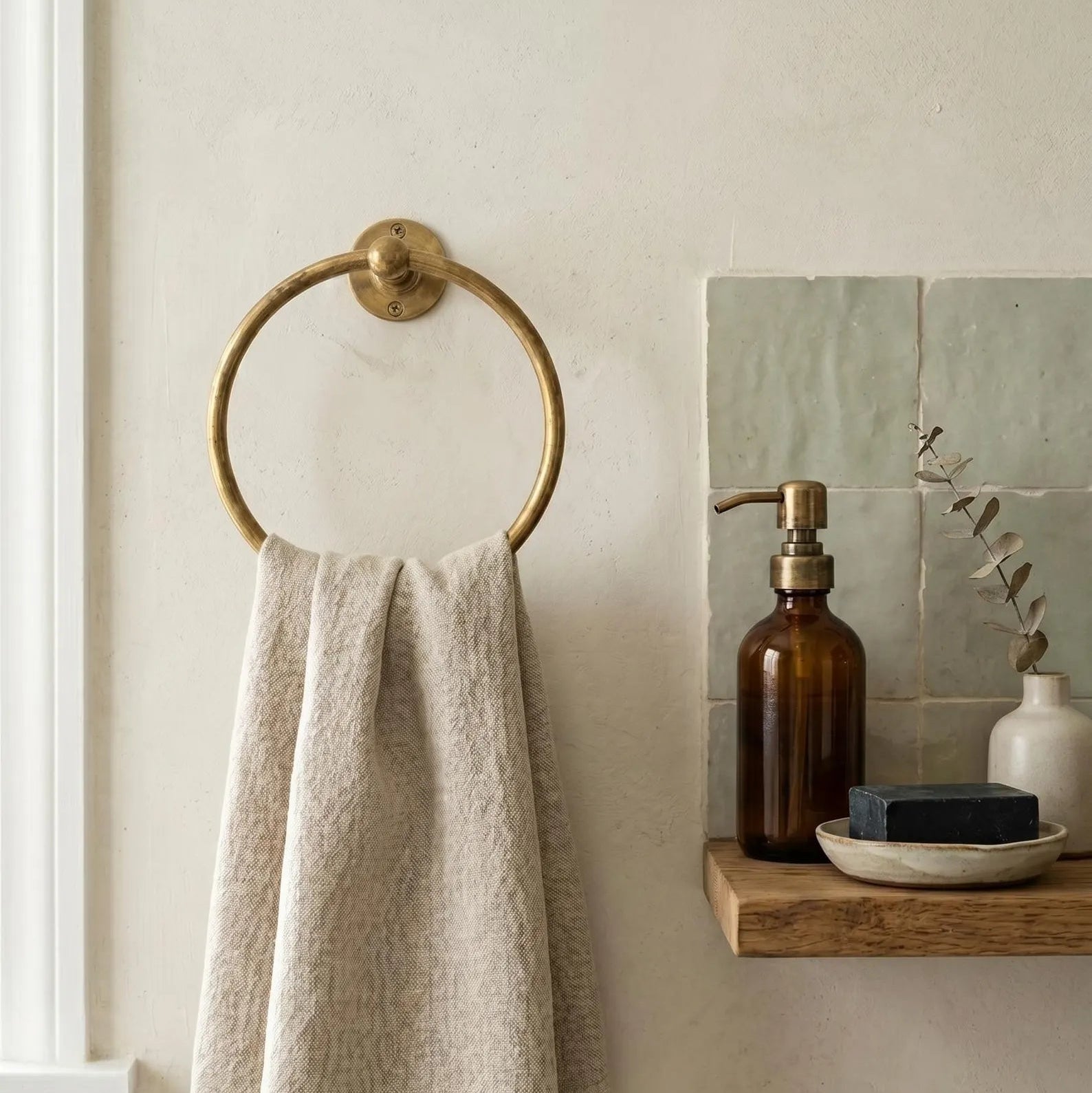 Beige towel hanging on a gold towel ring in a bathroom setting.
